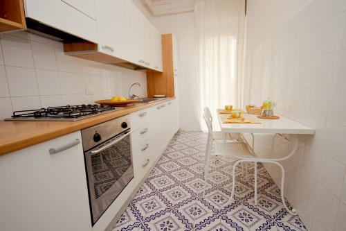 a white kitchen with a stove and a table at Apt luminoso, spazioso con Aria condiz e bici in Viareggio