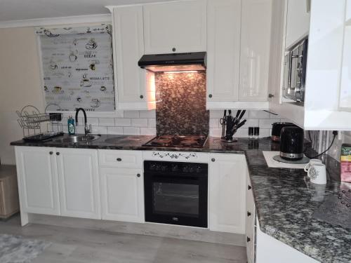 a kitchen with white cabinets and a stove top oven at Cozy Cabin in Midrand