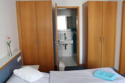ein Schlafzimmer mit einem Bett und ein Badezimmer mit einem Waschbecken in der Unterkunft Gästehaus Germania in Wangerooge