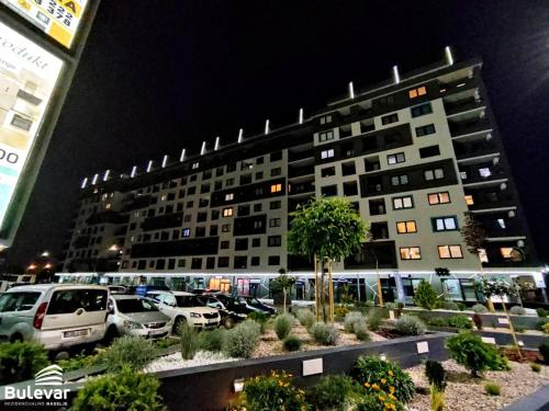 a large building with cars parked in a parking lot at Delux Apartmani Bulevar in Sarajevo