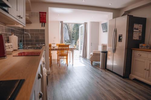 a kitchen with a refrigerator and a table with chairs at Riverbank Cottage in Ironbridge