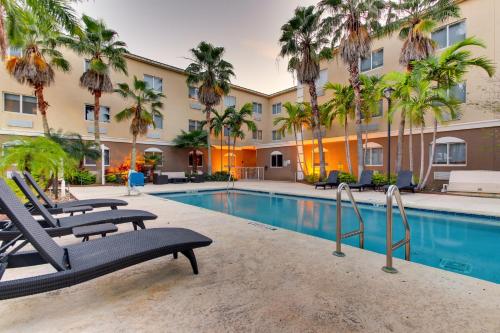 a swimming pool with chairs and palm trees in front of a hotel at Holiday Inn Express West Palm Beach Metrocentre by IHG in West Palm Beach