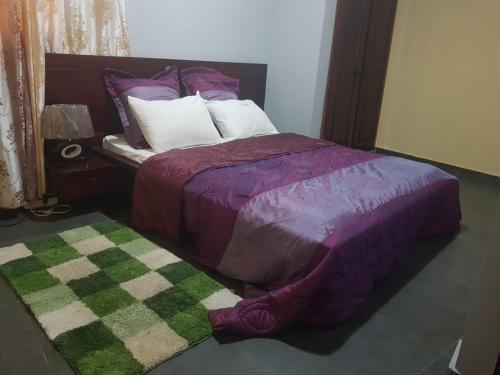 een slaapkamer met een bed en een groene en paarse deken bij LE MILAN ( appartements et chambres meublés ) in Douala