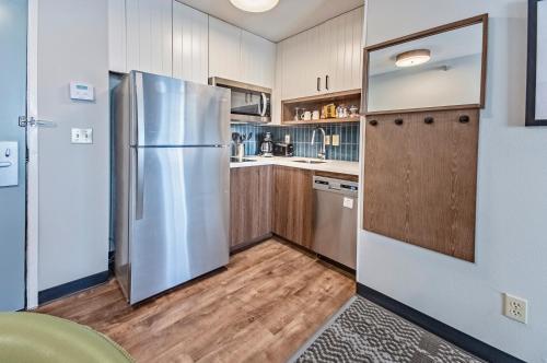 a kitchen with a stainless steel refrigerator and wooden cabinets at Staybridge Suites - Cedar Rapids North by IHG in Cedar Rapids