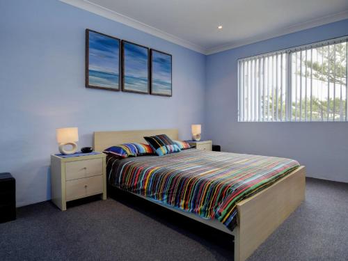 a bedroom with a bed with blue walls and a window at Anchorage 7 in Tuncurry
