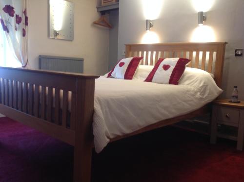 una camera con letto in legno e cuscini rossi e bianchi di Afon Duad Inn and Dolau Cottage a Cwm-Duad