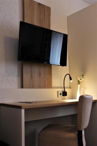 a desk with a television on a wall at Hotel Berghof Wasserkuppe & Gästehaus Fuldaquelle in Gersfeld