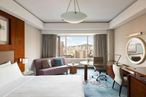 una camera d'albergo con letto, scrivania e sedia di Shangri-La Qingdao - May Fourth Square a Qingdao