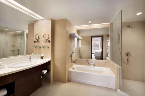 a bathroom with a tub and a sink and a shower at Shangri-La Qingdao - May Fourth Square in Qingdao
