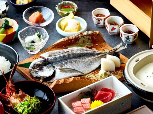 a table with a fish on a cutting board with other foods at Kazenokaori Mori Premier in Ito