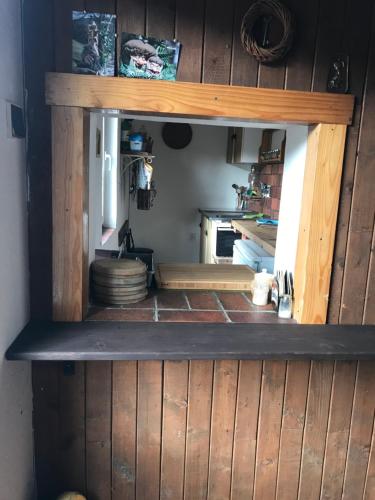 a kitchen with a wooden wall with a shelf at Horská chata na Brčálníku v srdci Šumavy in Železná Ruda