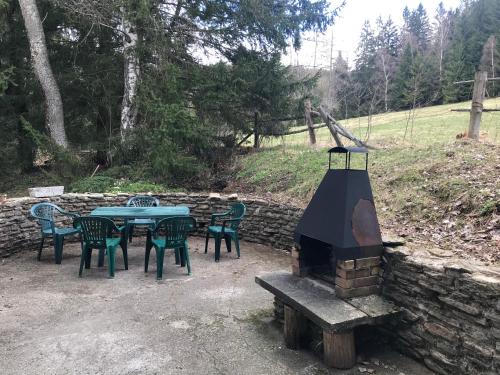 a table and chairs with a fireplace next to a stone wall at Horská chata na Brčálníku v srdci Šumavy in Železná Ruda