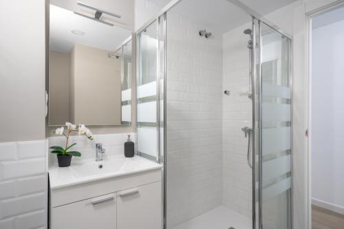 La salle de bains blanche est pourvue d'un lavabo et d'une douche. dans l'établissement Apartamento Barbados, à Fuengirola