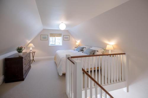 a white bedroom with a bed and a staircase at The Coach House Eyke Air Manage Suffolk in Woodbridge