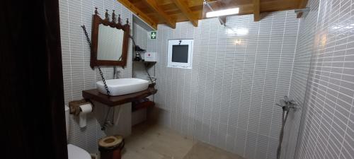 La salle de bains est pourvue d'un lavabo, d'un miroir et de carrelage blanc. dans l'établissement Casa da Bisa - Santa Maria - Açores, à Santa Bárbara