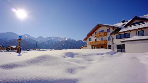a snow covered yard with a house and mountains at Apart-Hotel Dreisonnenhof in Fiss
