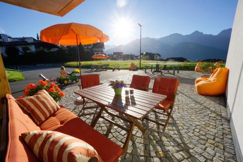 a wooden table with chairs and an umbrella at Apart-Hotel Dreisonnenhof in Fiss