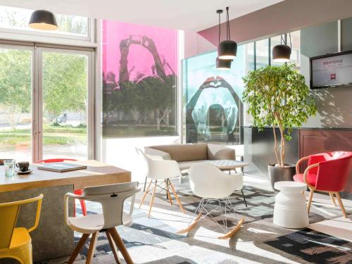 カリュイール・エ・キュイールにあるibis Lyon Caluire Cité Internationaleの椅子、テーブル、ソファが備わる客室です。
