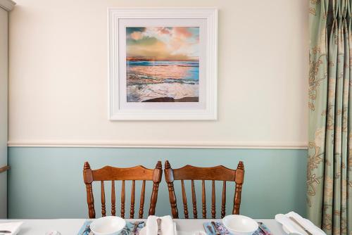 uma mesa com duas cadeiras e uma foto na parede em Klondyke House B&B em Waterville