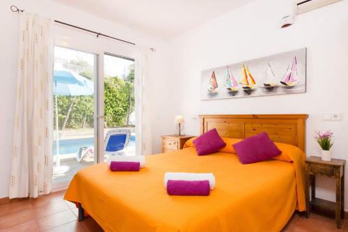 a bedroom with a large orange bed with purple pillows at Villa Romani by Villa Plus in Arenal d'en Castell