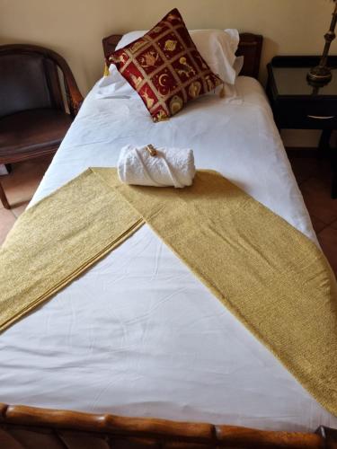 a bed with white sheets and two towels on it at Camelia Guest House in Universitas
