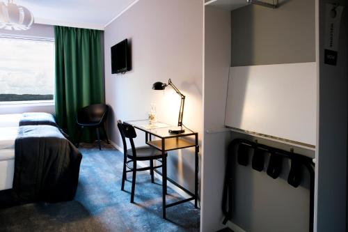 a hotel room with a bed and a desk with a lamp at Welcome Hotel Barkarby in Järfälla