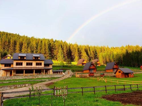a rainbow in the sky over a farm with a house at Etno selo Zminica in Žabljak