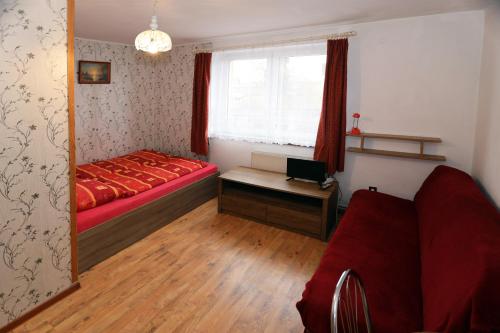 a bedroom with a red bed and a window at Pokoje Goscinne "Anna Maria" in Łeba