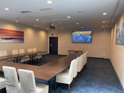 a conference room with a long table and white chairs at Ezüsthíd Hotel in Veszprém