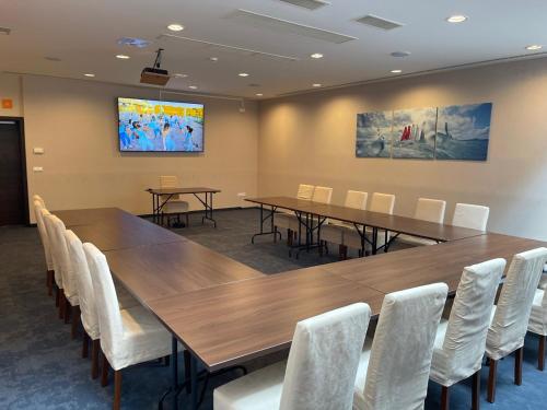 a conference room with wooden tables and white chairs at Ezüsthíd Hotel in Veszprém