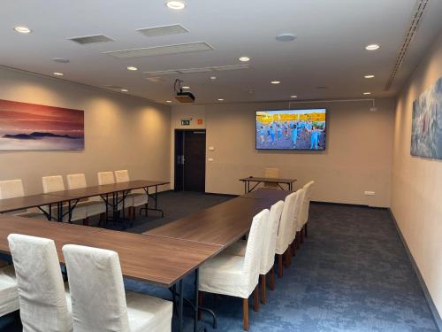 a conference room with a long table and white chairs at Ezüsthíd Hotel in Veszprém