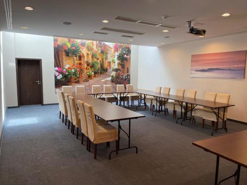 a conference room with tables and chairs and a painting at Ezüsthíd Hotel in Veszprém