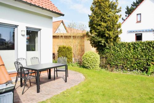 een terras met een tafel en stoelen in een tuin bij DEB 041 Ferienwohnung am Kurpark A in Altefähr