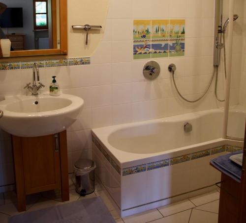 a bathroom with a sink and a bath tub next to a sink at Ferienwohnung Fanese in Flintsbach