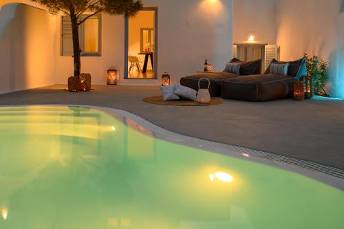 a large swimming pool in a living room with a couch at Este Luxury Suites in Fira
