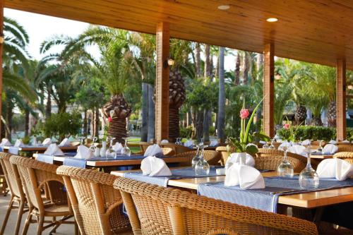 a restaurant with tables and chairs and palm trees at Meryan Hotel - Ultra All Inclusive in Okurcalar