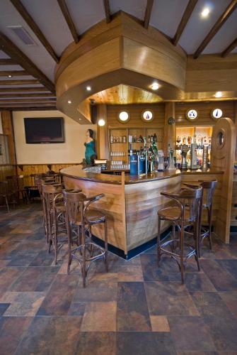 a bar in a restaurant with wooden walls and stools at Beach Hotel & Restaurant in Downings