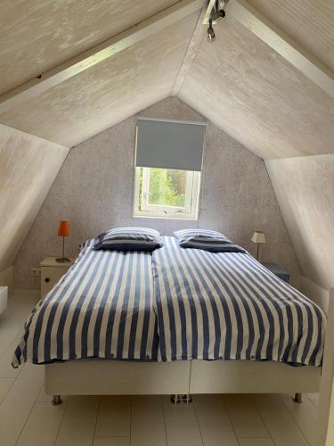 a bed in a attic room with a window at De Vuurdoorn in Bergen