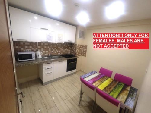 a kitchen with white cabinets and a table with pink chairs at !FEMALES ONLY! Bakırköy Elit Kiz Yurdu in Istanbul