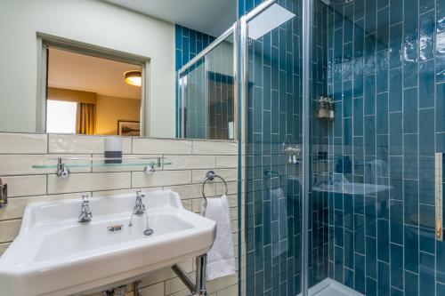 a bathroom with a sink and a glass shower at Riva Boutique Hotel in Helensburgh