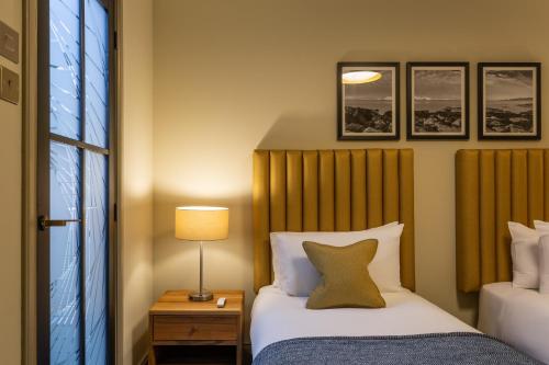 a bedroom with two beds and a lamp and a window at Riva Boutique Hotel in Helensburgh