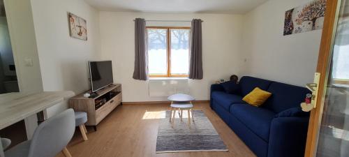 a living room with a blue couch and a tv at La Cabane de Fierville in Fierville-les-Parcs