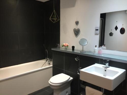 a bathroom with a sink and a toilet and a bath tub at Stunning Glasgow City Centre Apartment in Glasgow