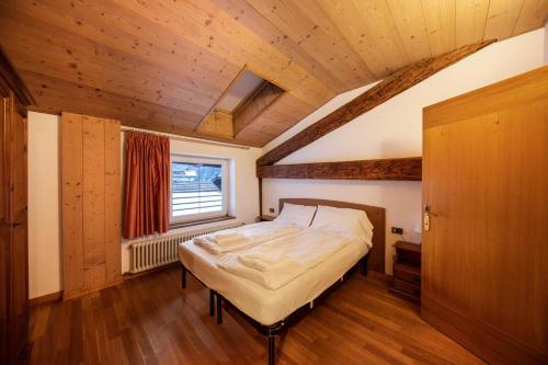 a bedroom with a bed and a window and wooden ceilings at Mandarda stile rustico 6/8 letti in Predazzo