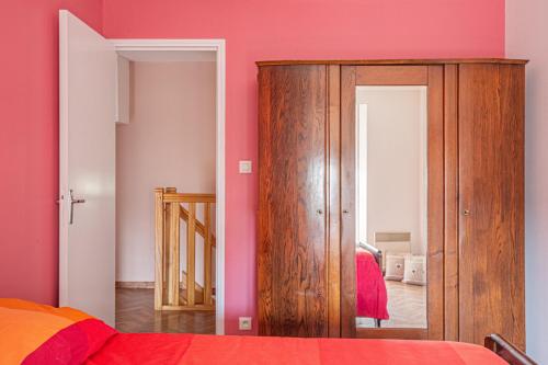 a bedroom with pink walls and a wooden cabinet at Gîte de la Forge in Millières