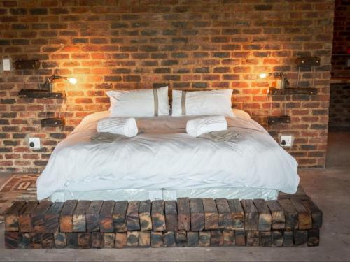 a bed in a room with a brick wall at The Ancient Copper Shed in Potchefstroom