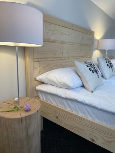 a bed with white pillows and a table with a lamp at Pienińska Ostoja in Czorsztyn