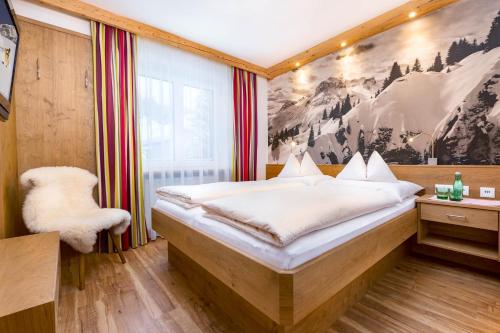 a bedroom with a bed with a painting on the wall at Hotel Garni Lavendel in Lech am Arlberg