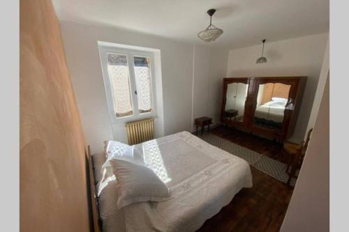 1 dormitorio con cama blanca y espejo en La Croquante face au château, en Beynac-et-Cazenac