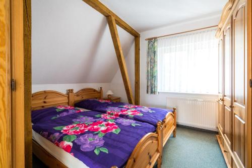 ein Schlafzimmer mit einem Bett mit einer lila Bettdecke und einem Fenster in der Unterkunft Ferienwohnung 3, Waldesruh Dierhagen in Dierhagen